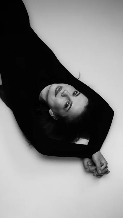 A woman in a black dress lies on her back