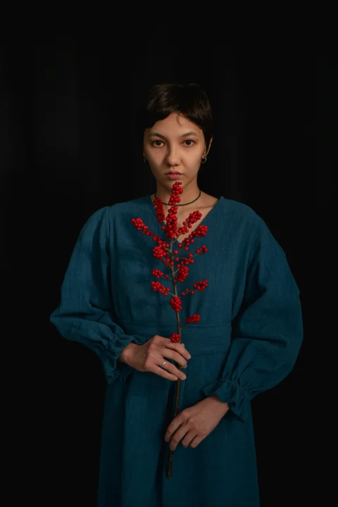 a woman in a blue dress holding a red flower