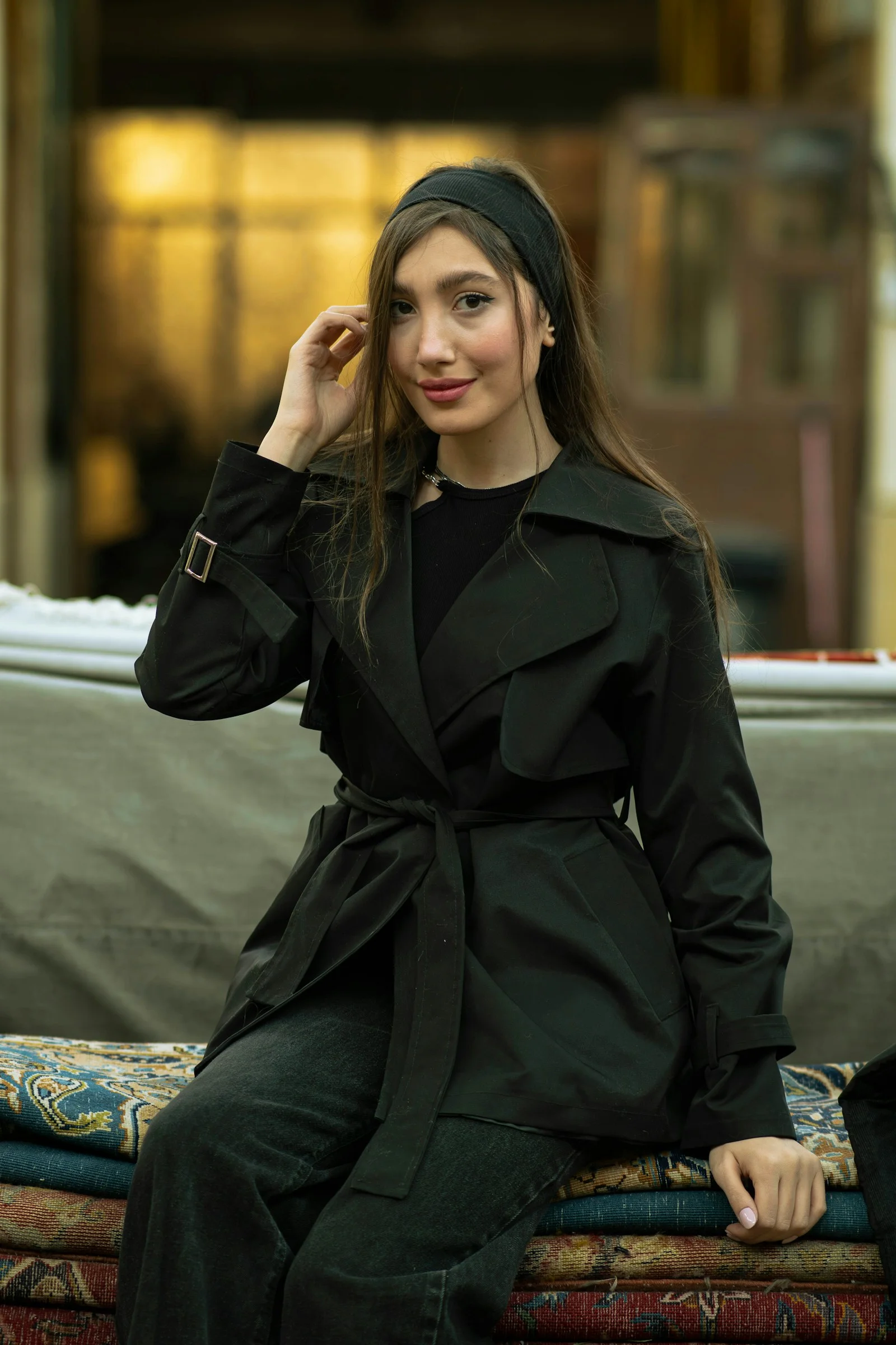 黒いトレンチコートを着た若い女性が微笑む