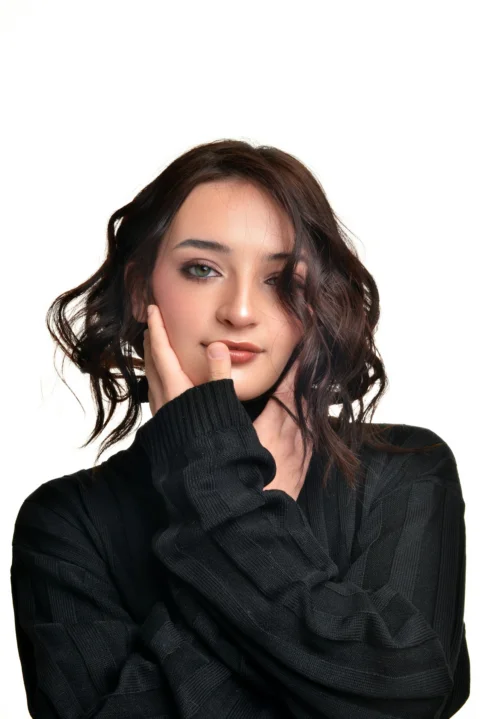 A young woman with dark wavy hair and makeup