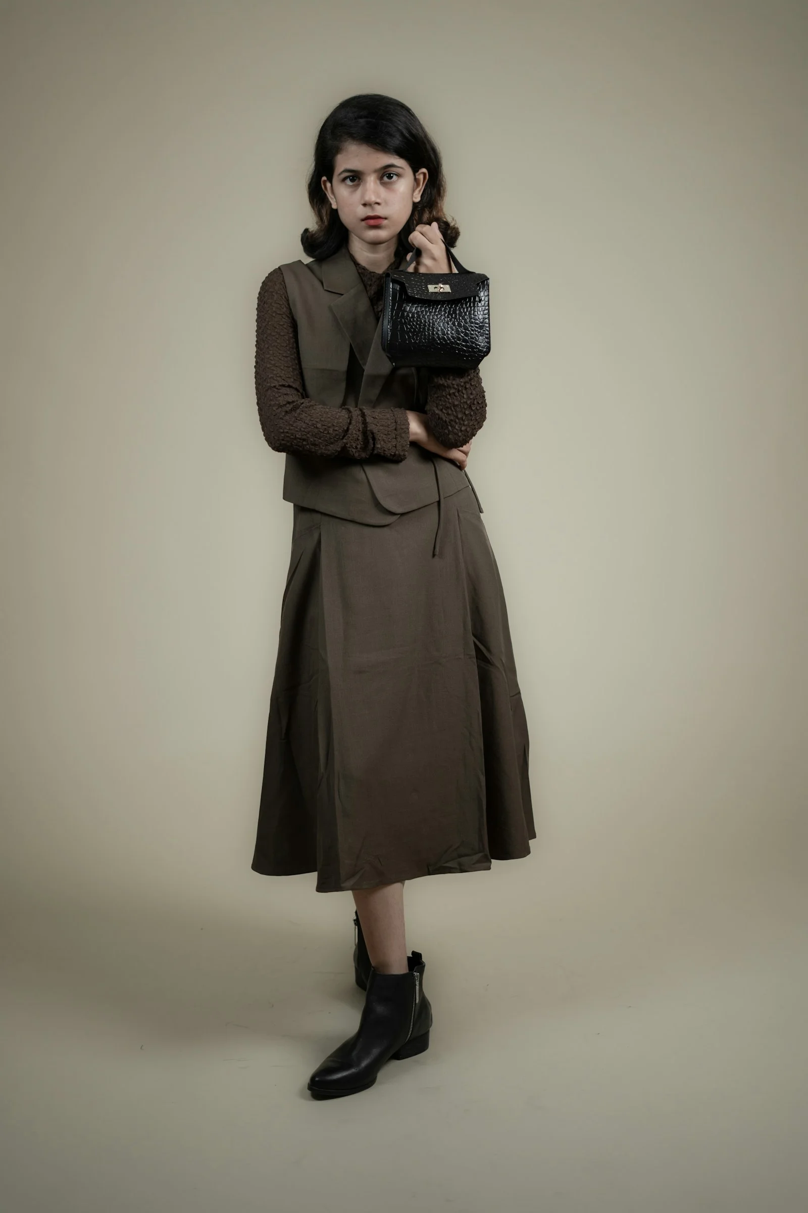 a woman in a brown dress holding a black purse