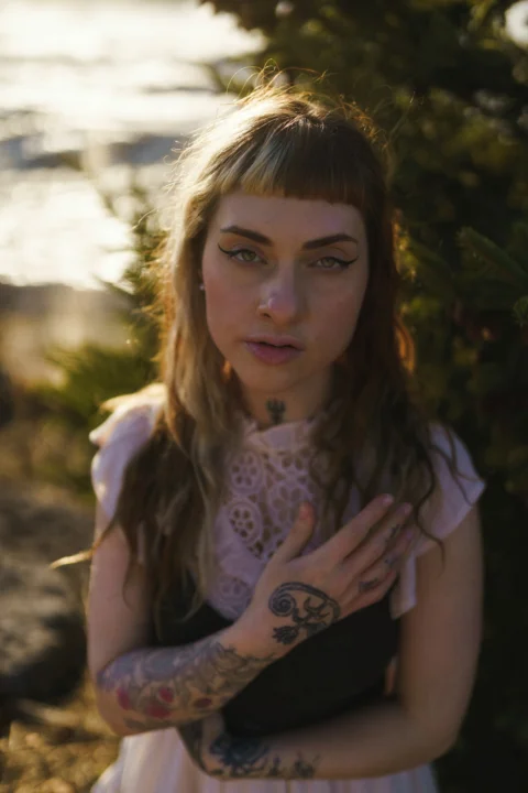 Woman with tattoos and bangs looking at camera