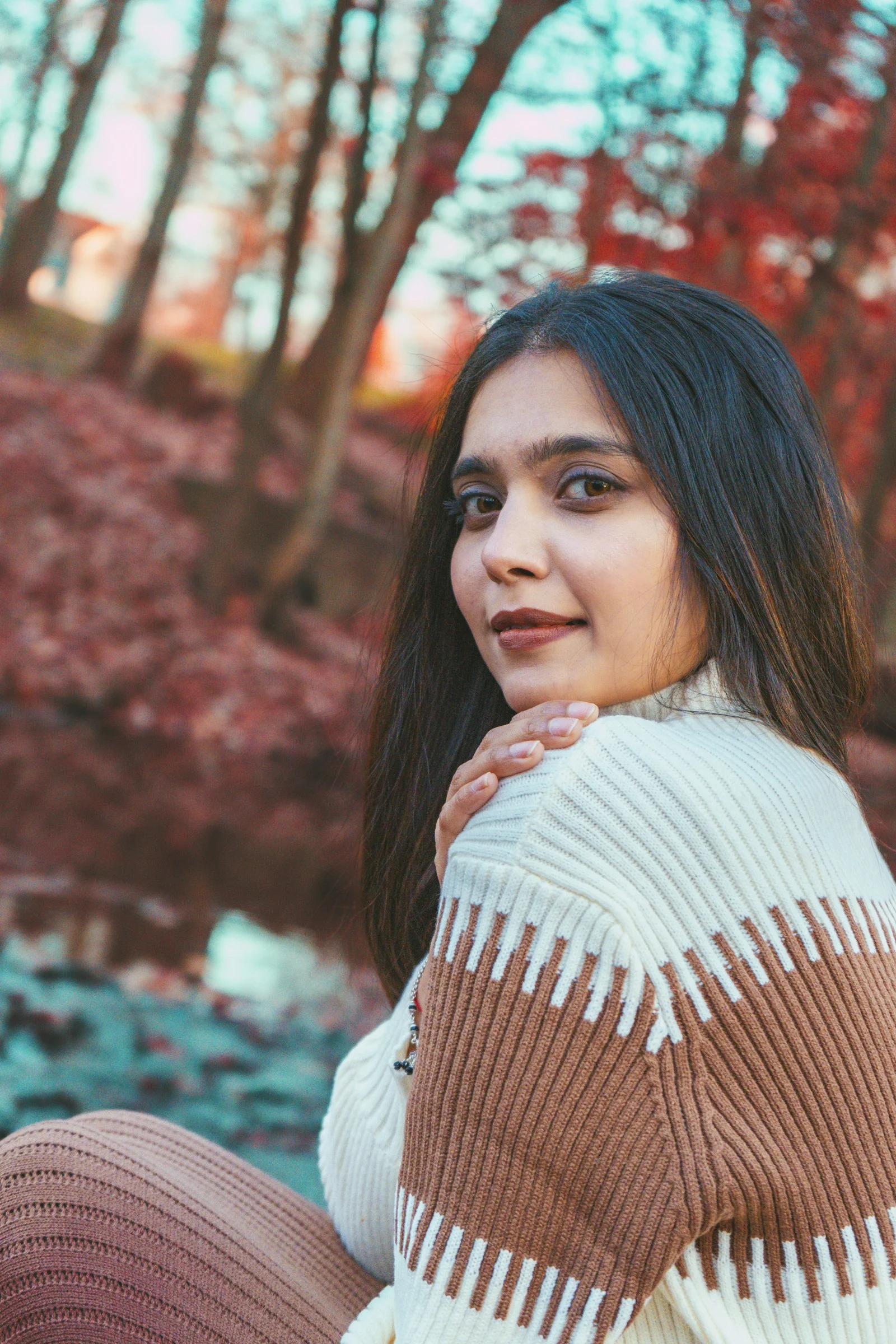 a woman sitting on the ground in front of some trees