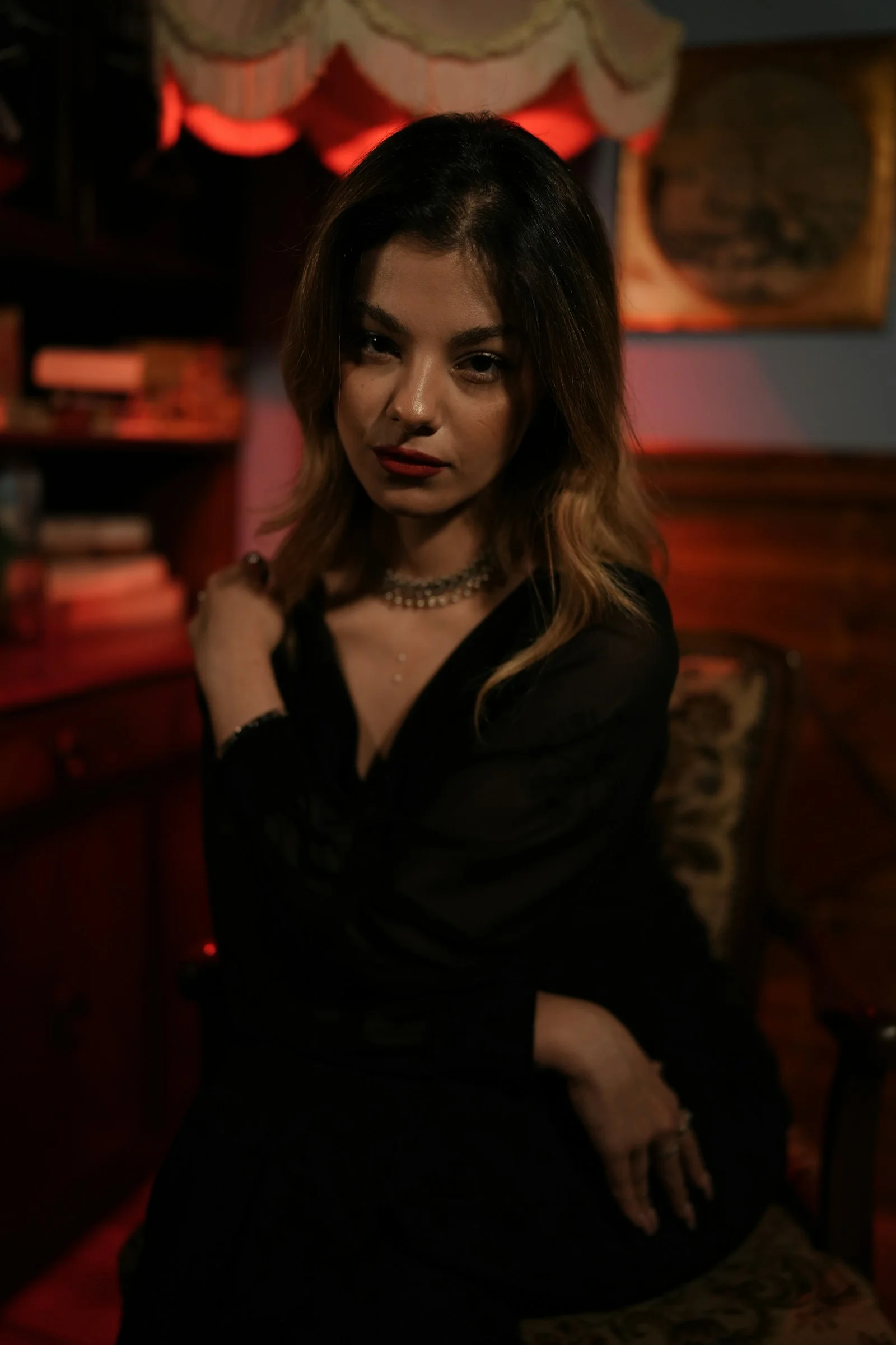 A woman in a black top sitting in a chair under red light