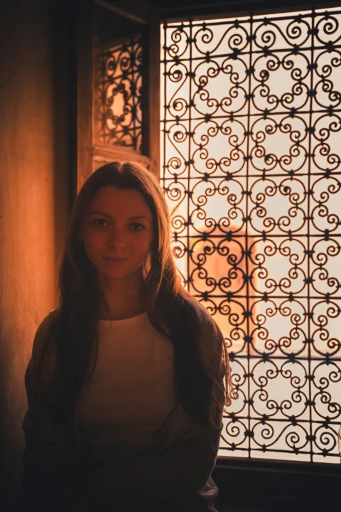 Young woman in front of ornate window at sunset