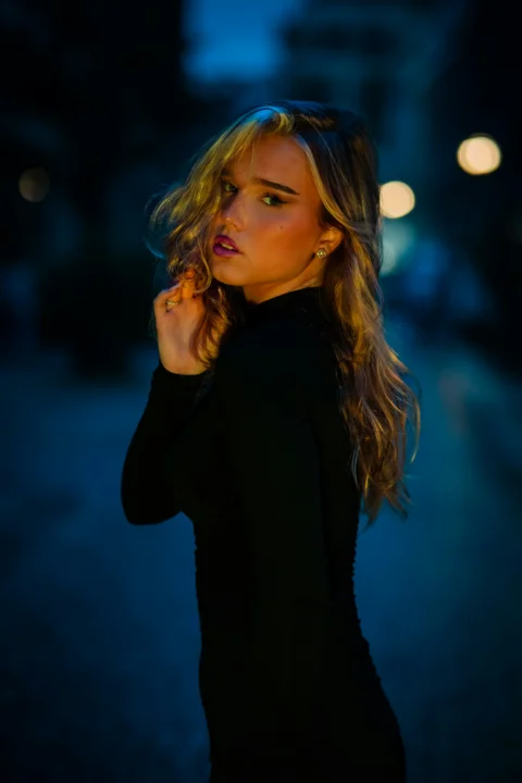 夜晚，一位身穿黑色长袖衬衫的女性沐浴在温暖的金色光线中