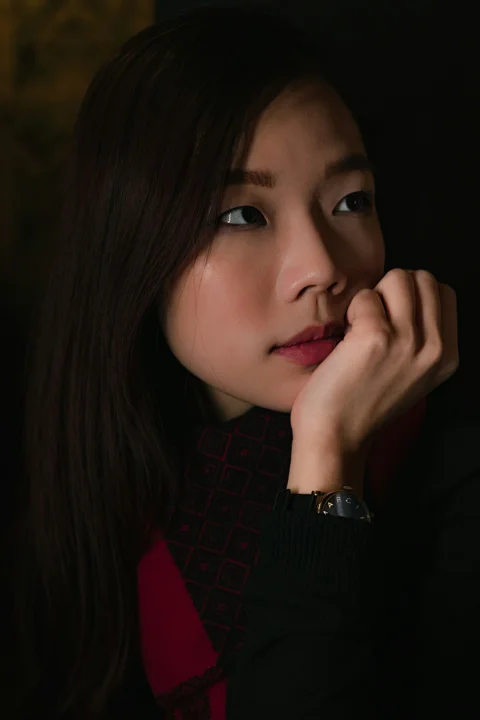 옆을 향해 선 검은 긴소매 상의 차림의 여성