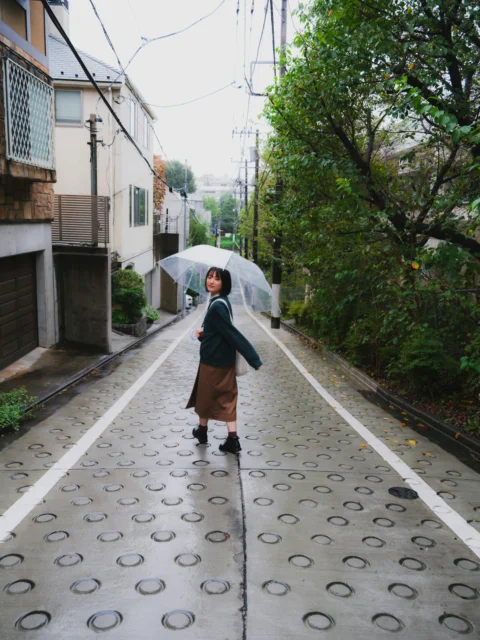 a woman walking down a street holding an umbrella