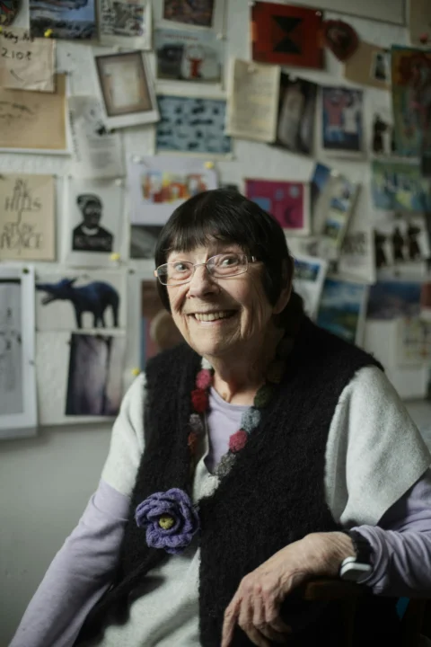 A woman sitting in a chair in front of a wall with pictures on it
