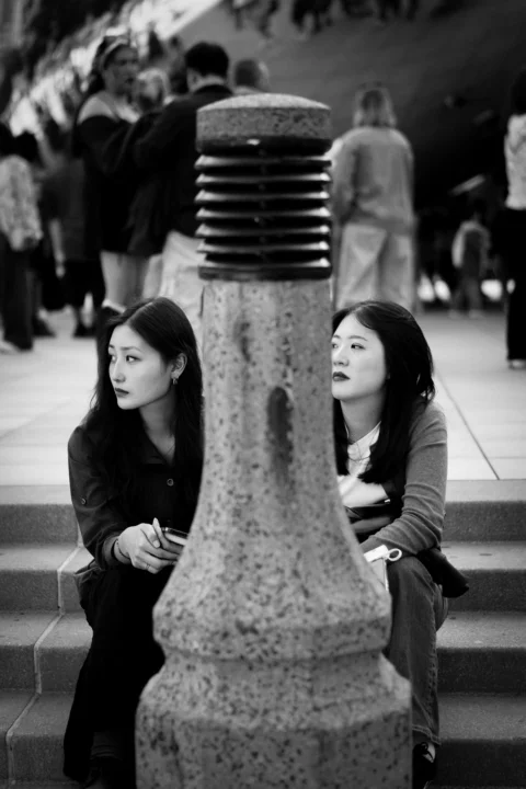 两名年轻的亚洲女性坐在带有立柱的台阶上