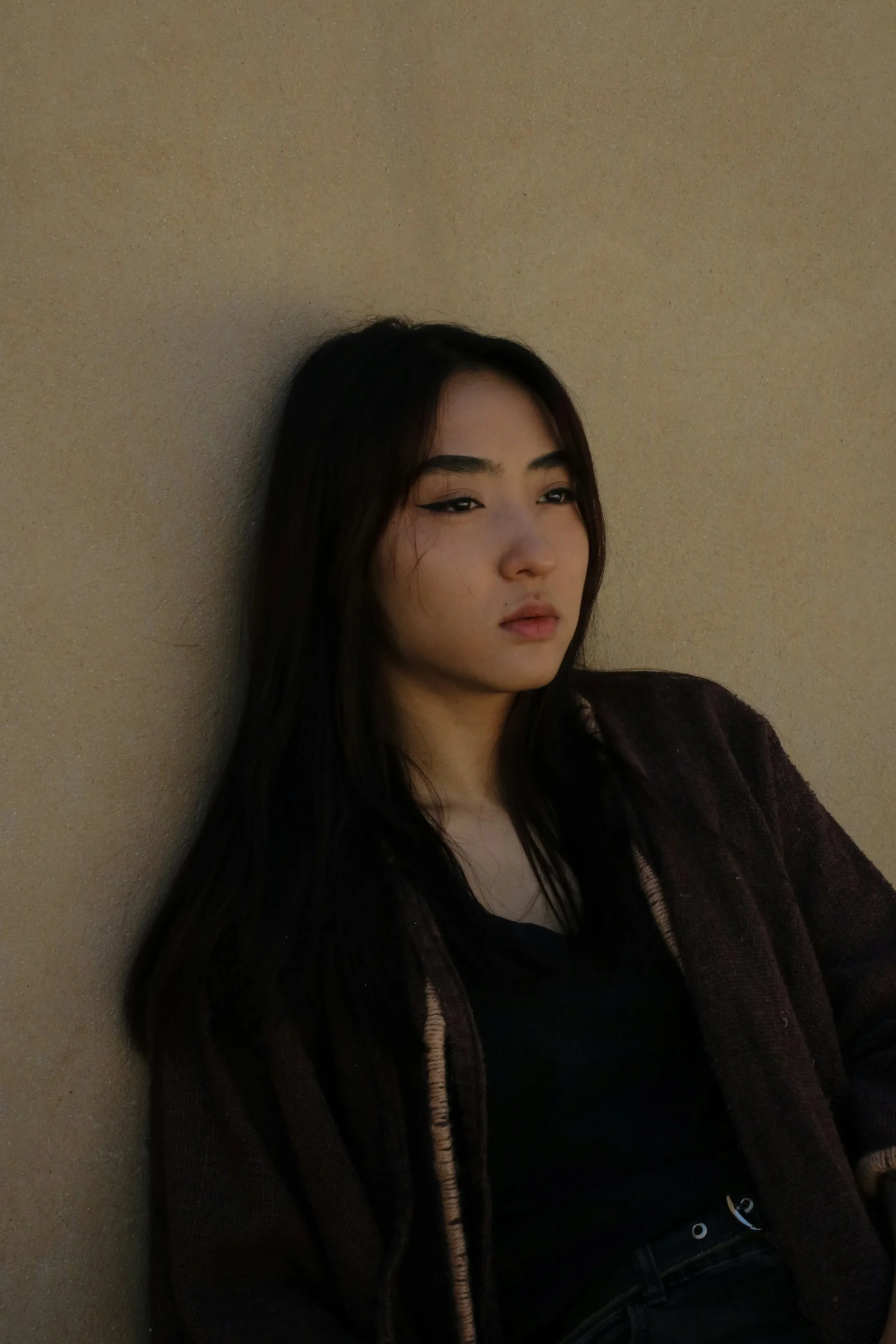 片手を腰に当てて壁にもたれる女性