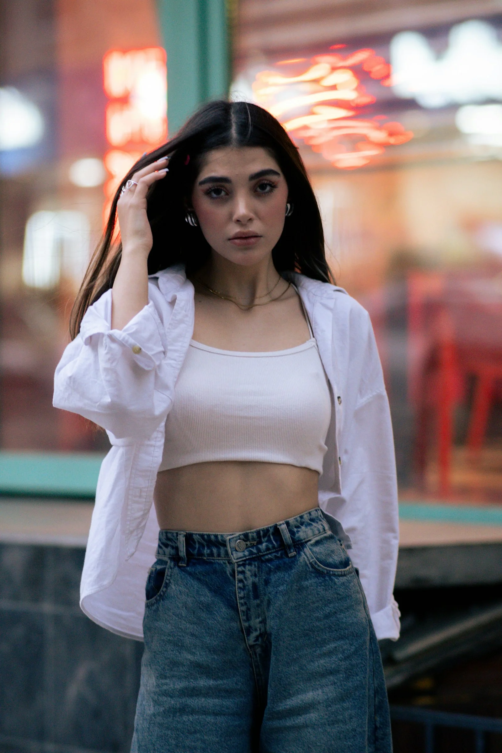 Woman poses in an urban setting, hands in hair
