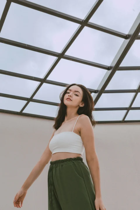 a woman in a white top and green pants