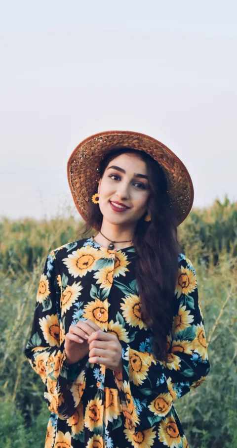 a woman wearing a sunflower print dress and a straw hat
