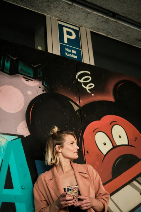 a woman standing in front of a mickey mouse wall