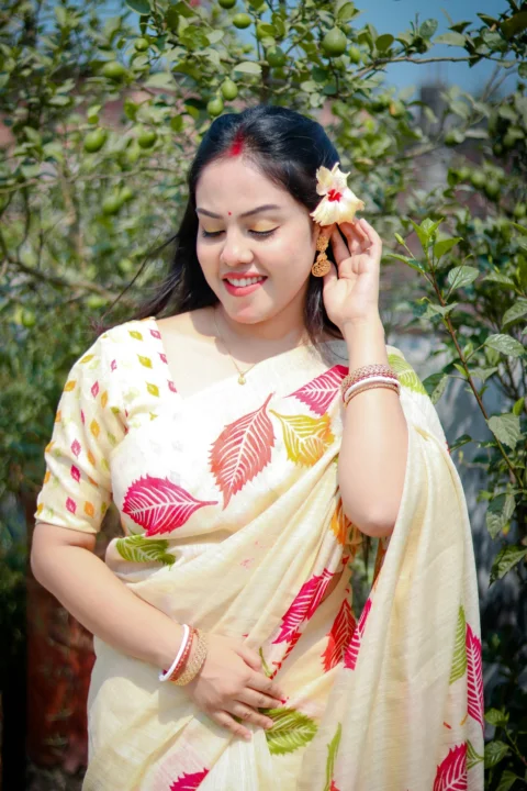 A woman smiles while wearing a floral saree