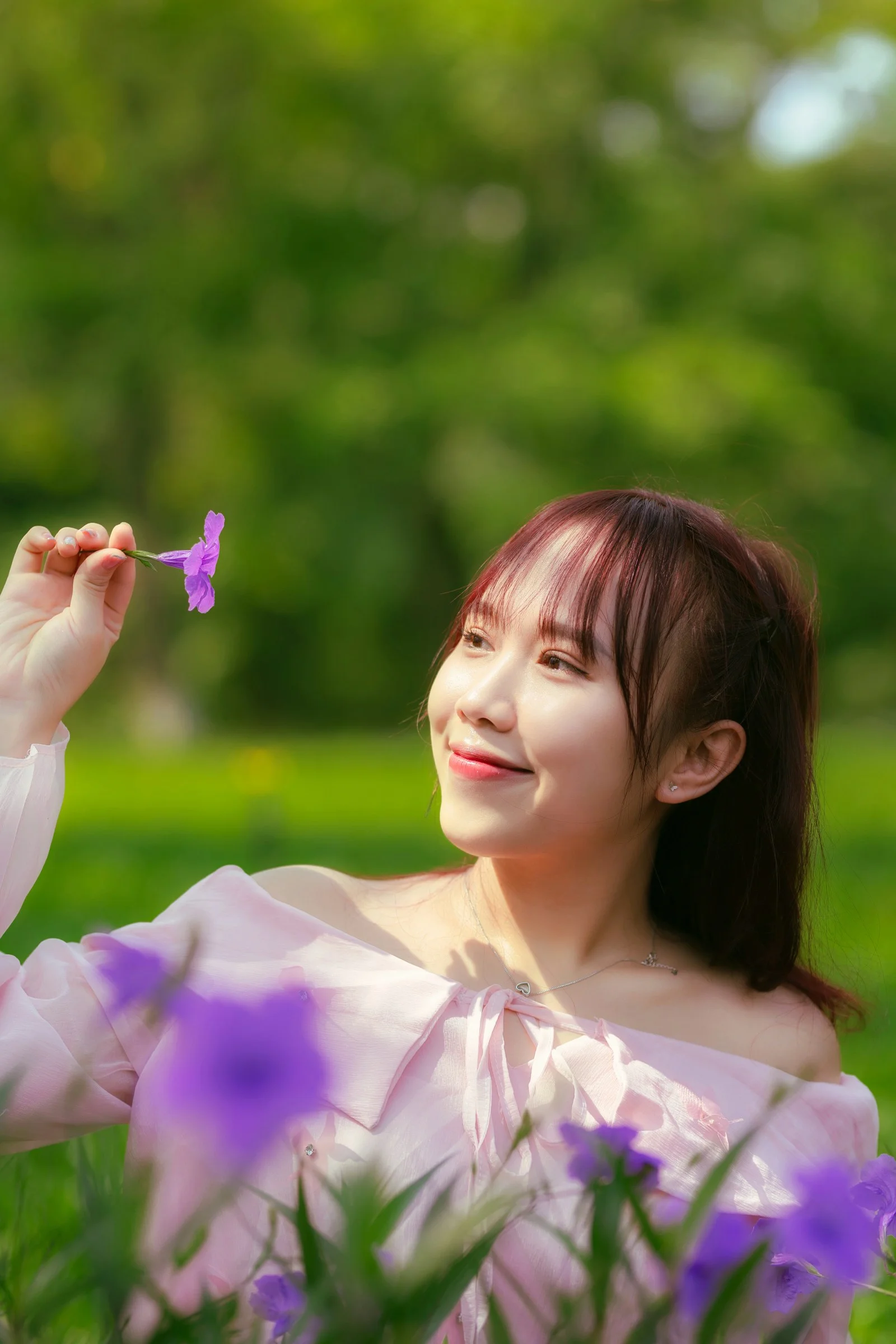 A woman sitting in the grass with a butterfly in her hand