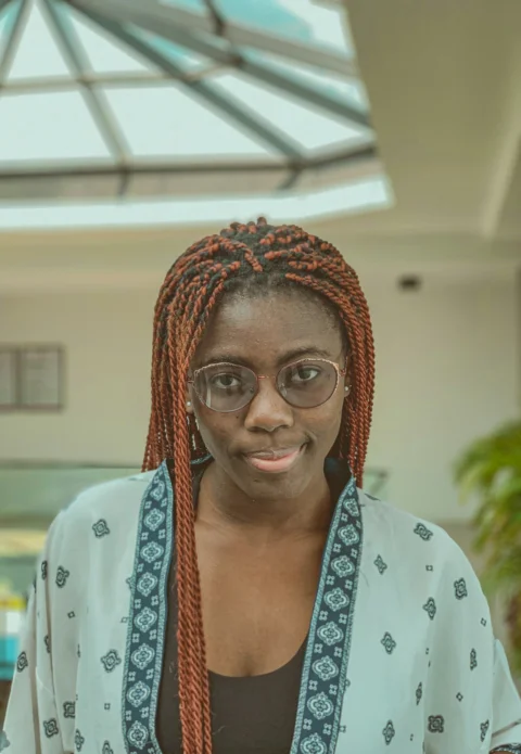 a woman with red hair and glasses standing in a room