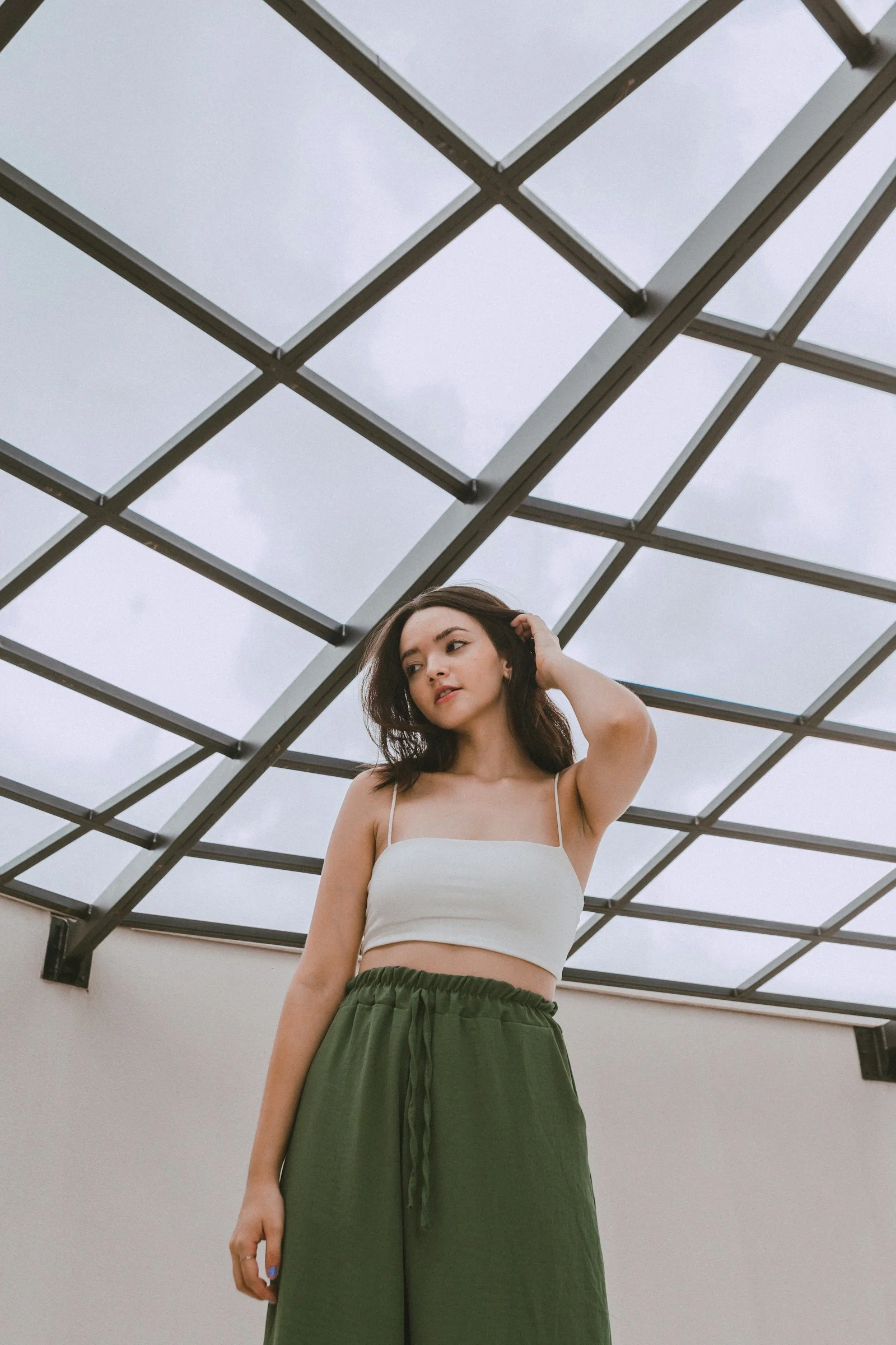 a woman in a white top and green pants