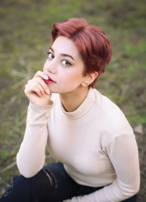 A woman with red hair poses outdoors