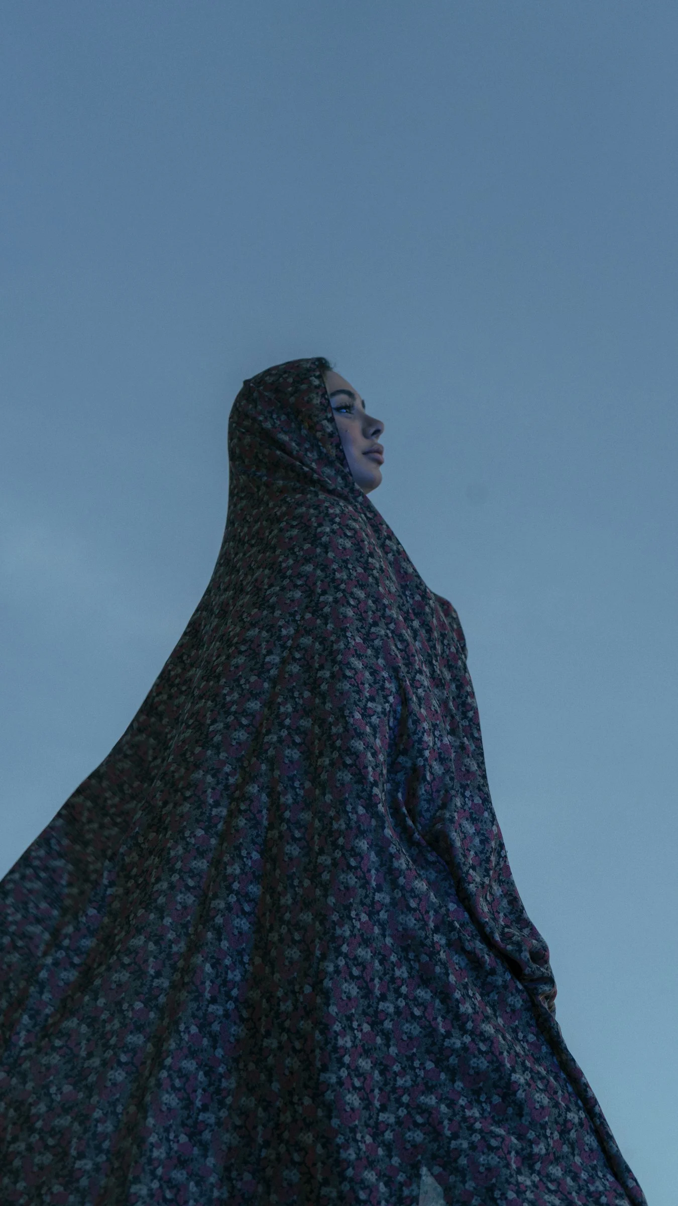 A woman wears a floral veil against blue sky