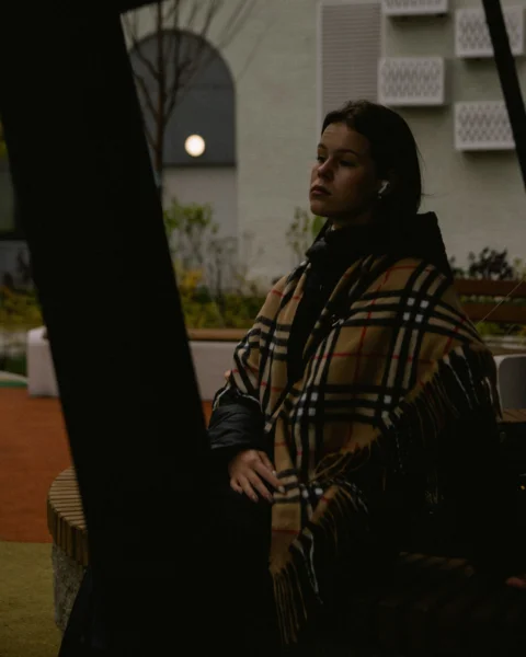 一名裹着毯子的女子坐在长凳上