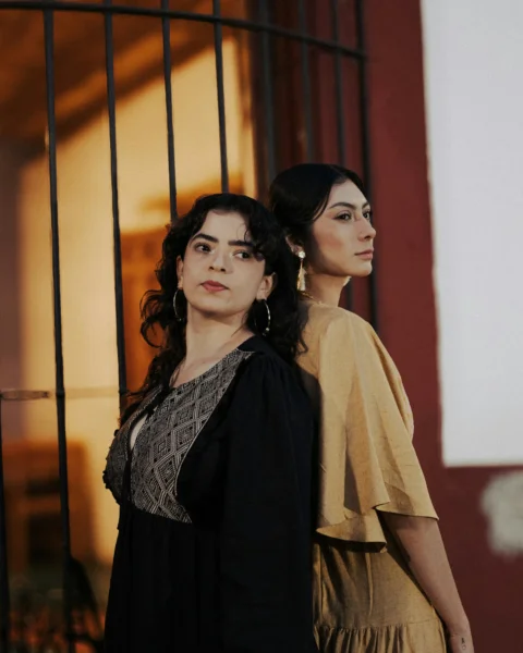 Two women stand back to back, striking a pose