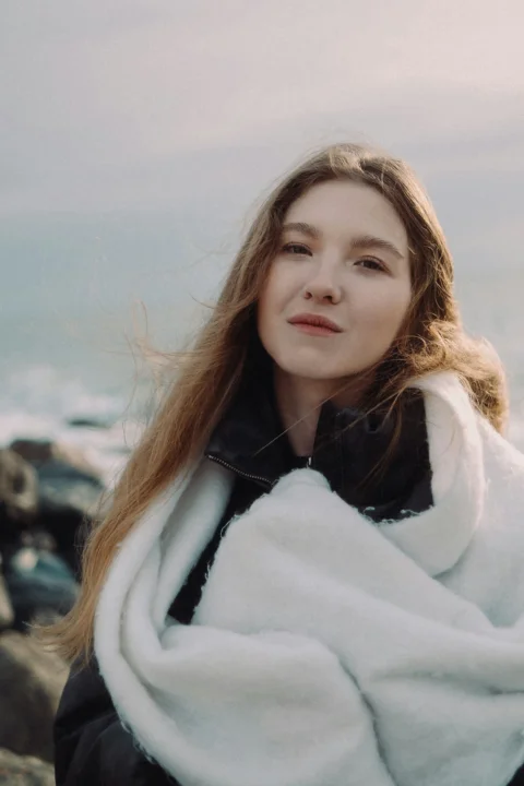 Beautiful woman with scarf smiles by the sea
