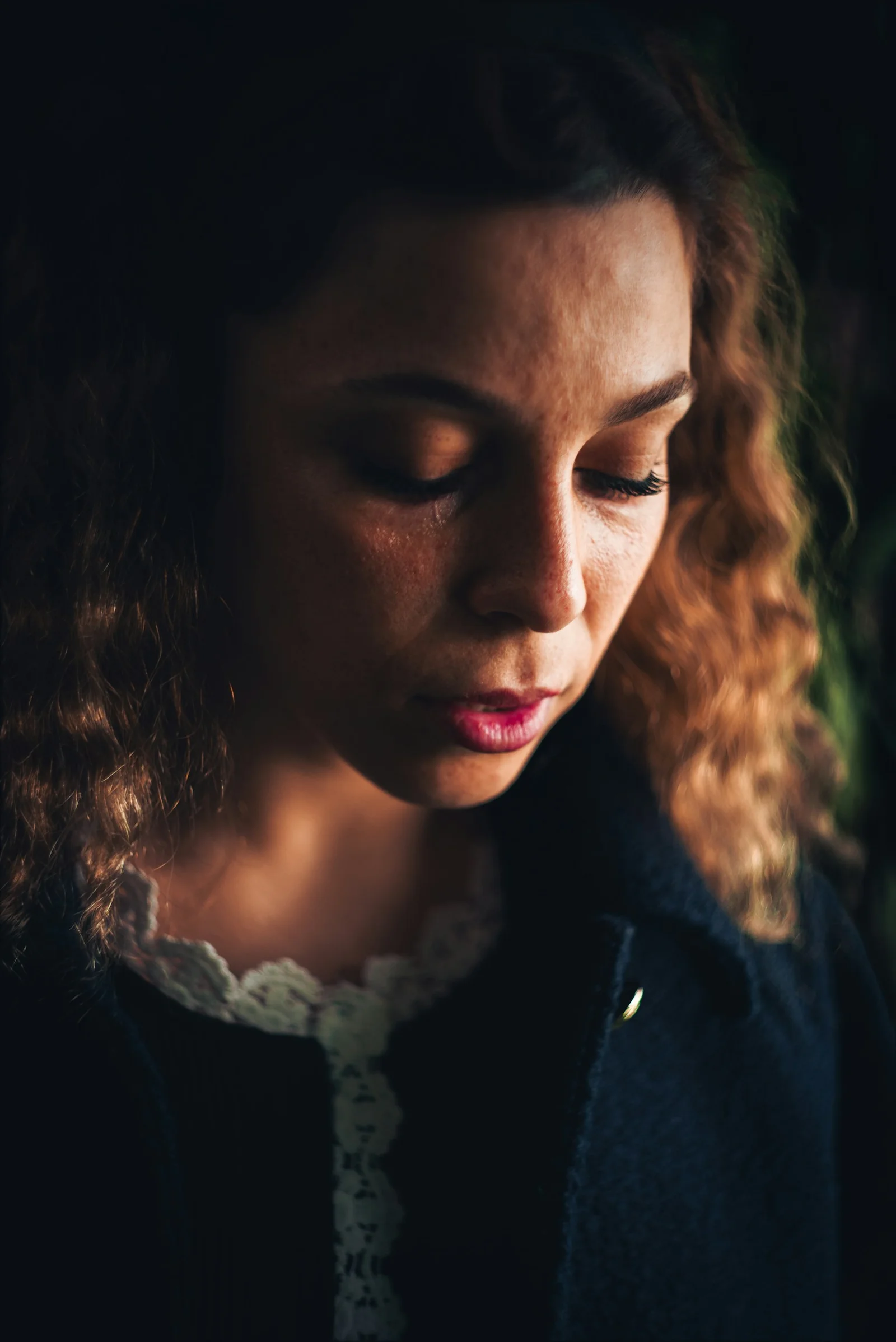A woman with curly hair looking down