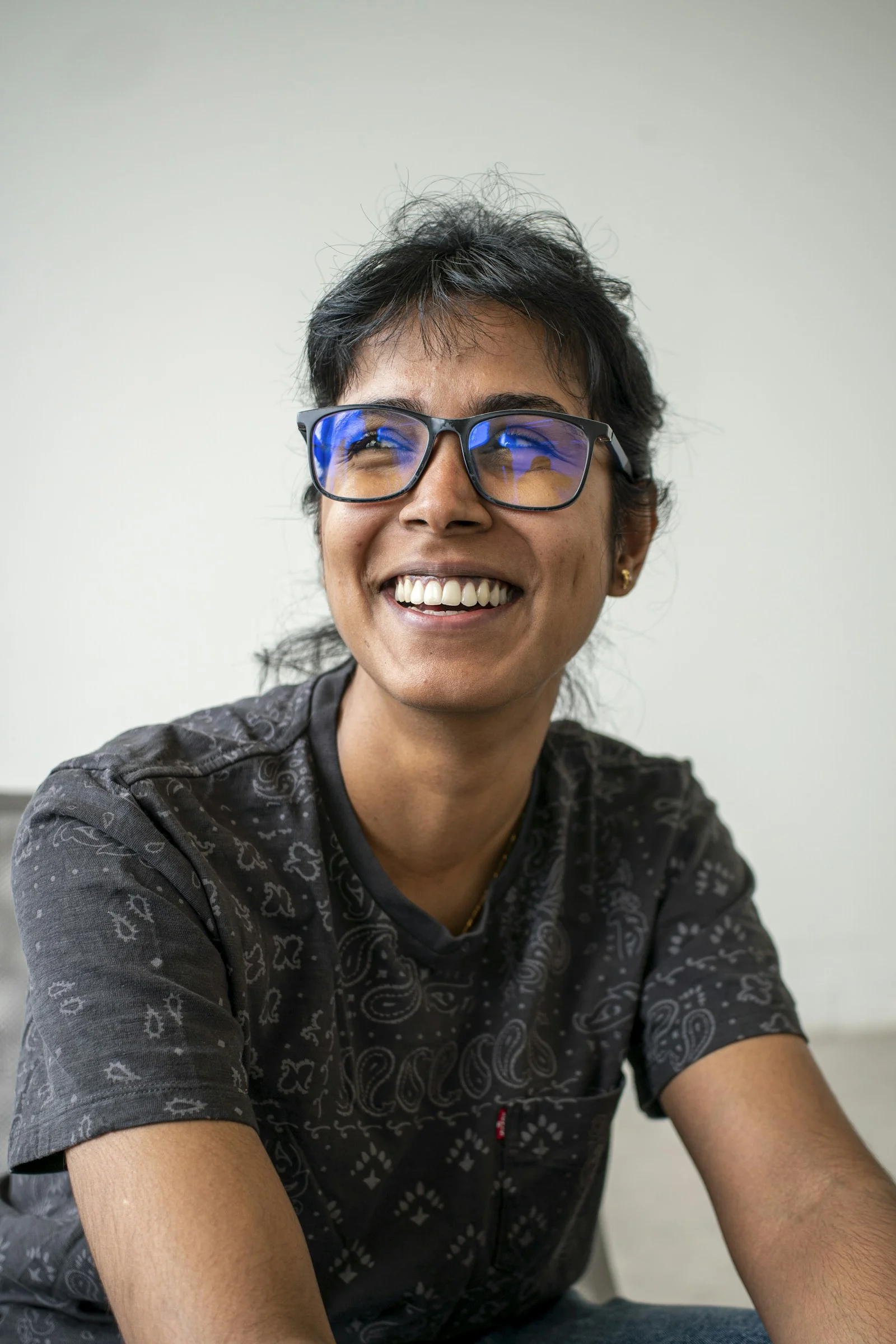 Woman with glasses smiles, looking upwards