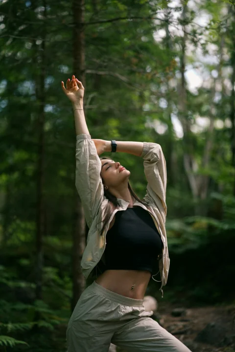 a woman standing in the middle of a forest