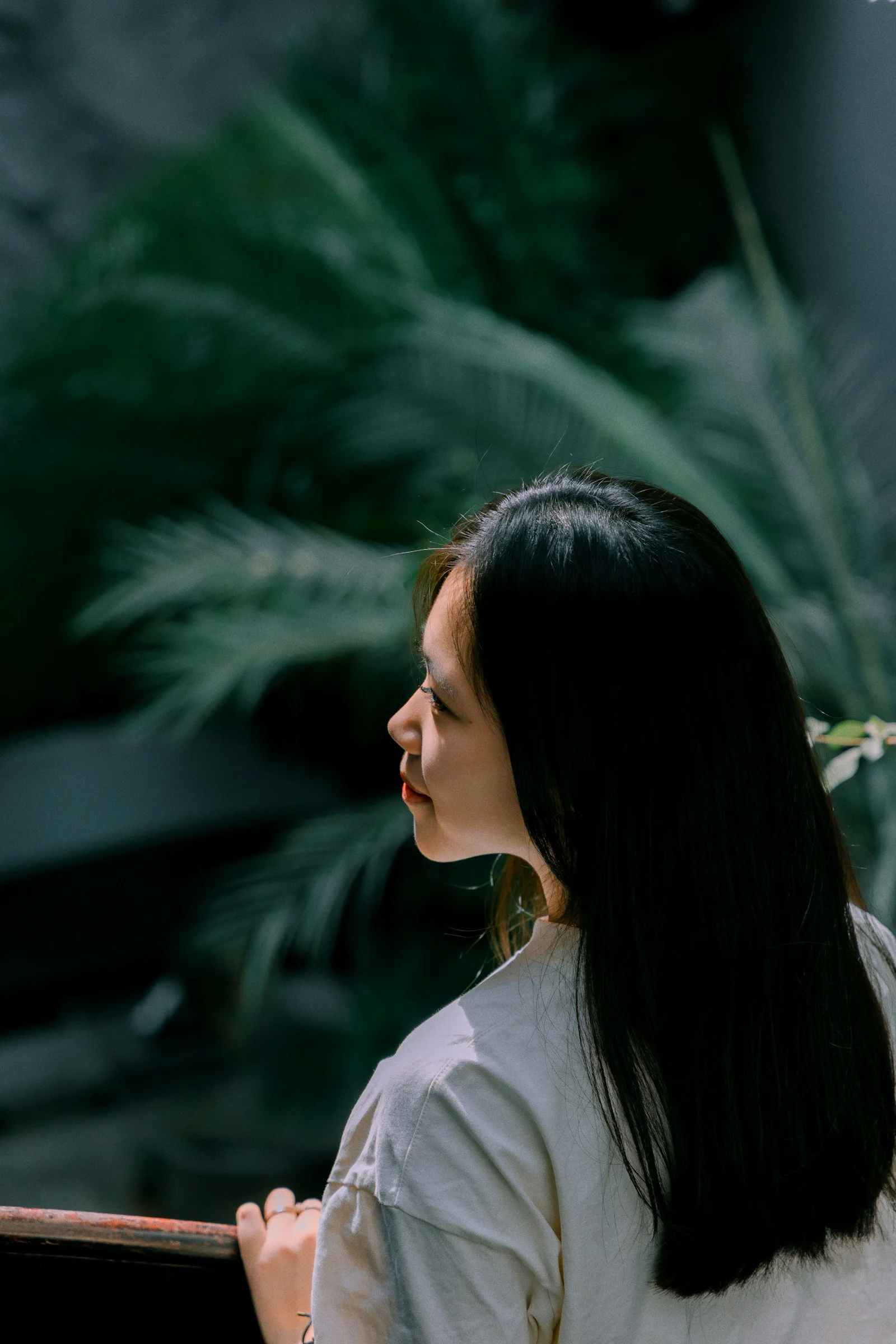A woman standing next to a window with a plant behind her