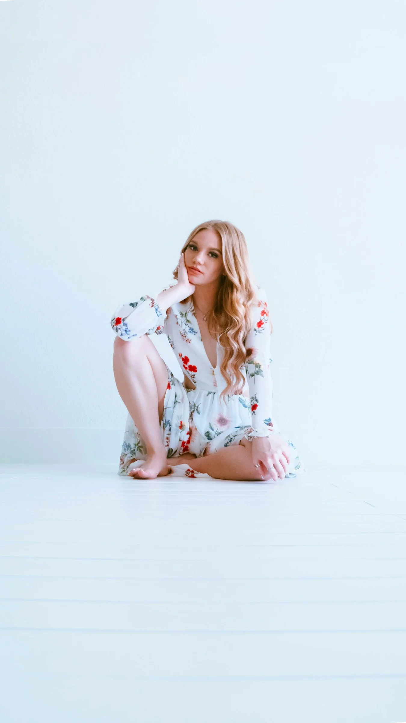 woman in white and red floral dress sitting on white floor